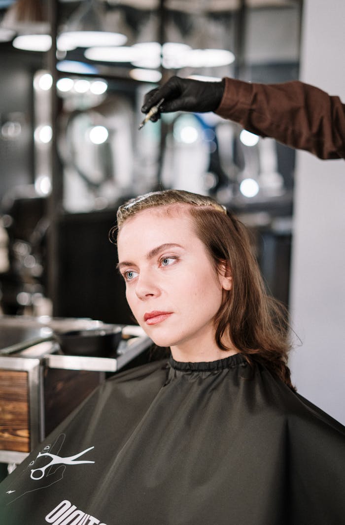 A woman gets her hair dyed by a professional stylist in a contemporary hair salon.