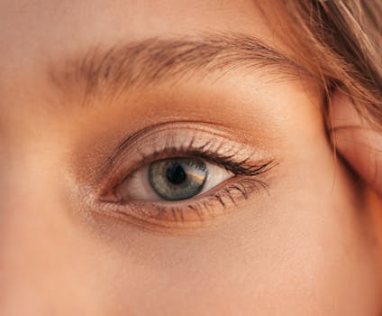 Detailed close-up of a human eye with visible eyelashes, skin texture, and natural lighting.